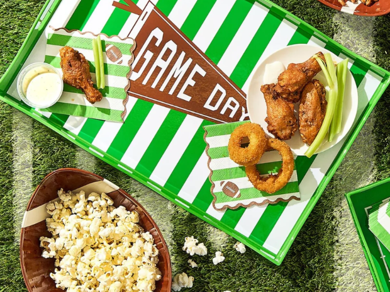 A tailgate party spread of food on football themed trays and dishes